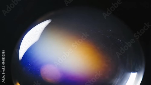 Close-up of a soap bubble with vibrant rainbow colors reflecting on its surface against a dark background.