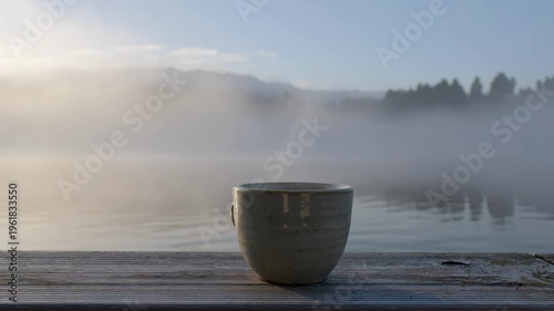 Morning coffee mug on a wooden pier by a misty lake. Seamless loooing 4k video background