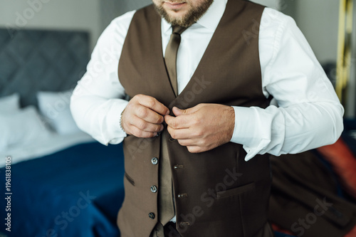 Groom Adjusting Brown Waistcoat and Suit Jacket During Wedding Preparations