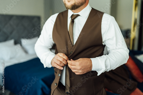 Groom Adjusting Brown Waistcoat and Suit Jacket During Wedding Preparations