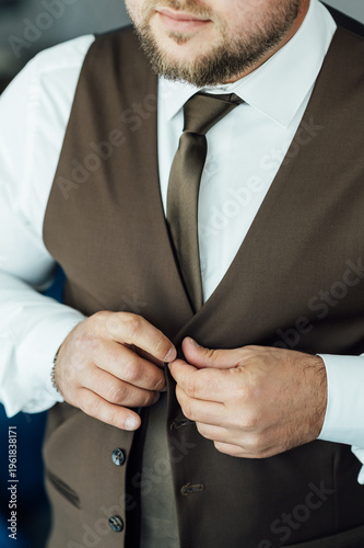 Groom Adjusting Brown Waistcoat and Suit Jacket During Wedding Preparations