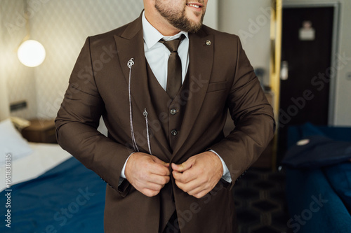Groom Adjusting Brown Waistcoat and Suit Jacket During Wedding Preparations