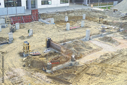 Fotografie Construction site with foundation layout and concrete columns arranged across sandy terrain