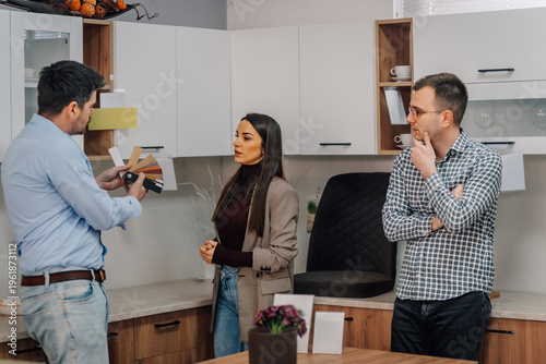 Couple consulting designer choosing kitchen materials for home renovation