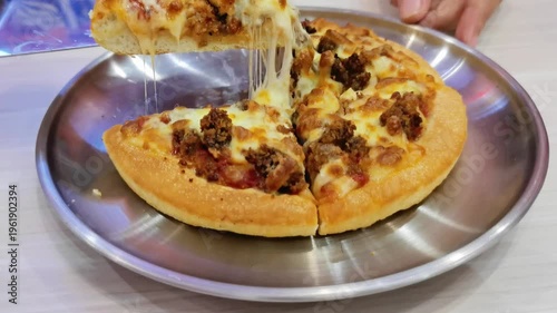 Delicious Beef and Melted Cheese Pizza Slice Being Lifted From a Metal Serving Plate