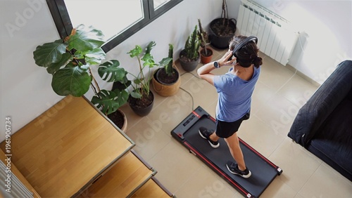 Photos Woman exercising on a smart treadmill at home, listening to music with headphone
