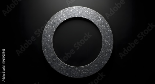 Industrial dark gray textured ring on a mysterious black background, highlighting its rough surface and perfect circular shape, a versatile mechanical part