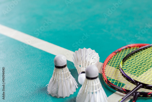 Badminton sport equipments, rackets and shuttlecocks on dark floor of indoor badminton court, soft focus, concept for badminton playing lovers around the world, copy space.