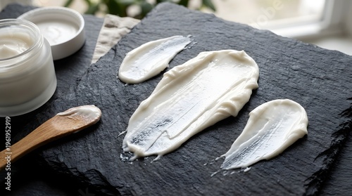A smear of white cream on a dark slate plate with a wooden spoon