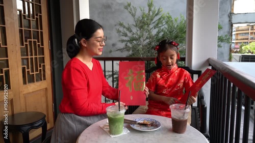Authentic family moment featuring a mother and child with oversized lucky red Angpao envelopes during Chinese New Year celebrations in a festive oriental setting.