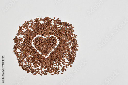 Brown flax seeds on a white background, flax seed heart, copy space for text