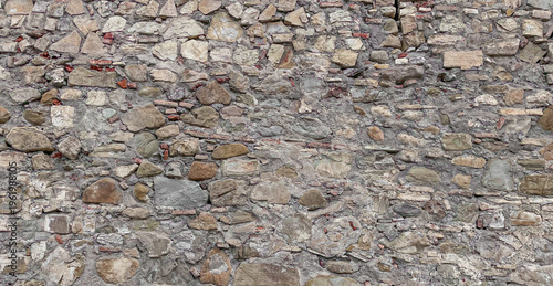 Ancient wall built by man from bricks and stones, brown background