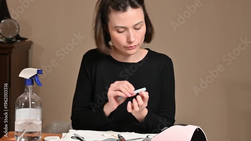 Young woman shaping nails with nail file at home
