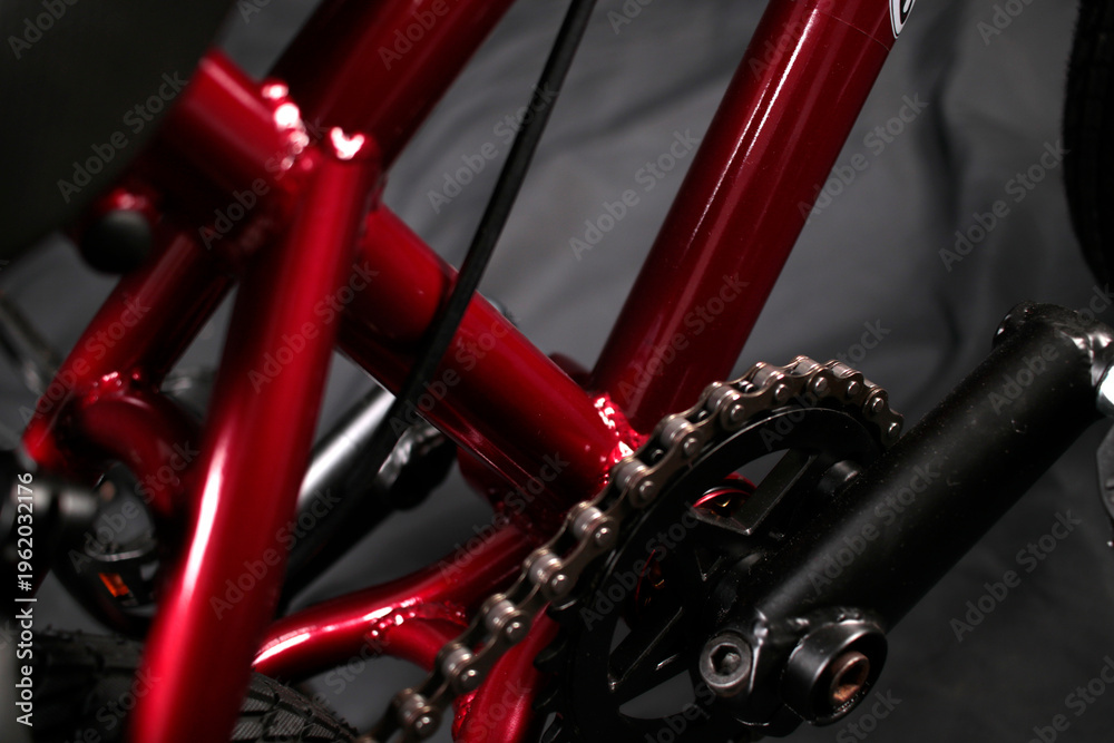 Fototapeta premium Macro shot of a red bicycle frame tube and a metal drive chain.