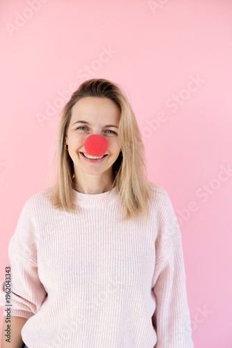 blond woman in front of pink background with red clown nose