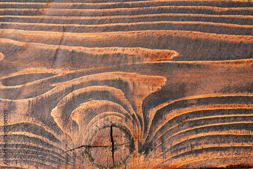 Close up of a dark stained pine wood surface showing natural grain patterns and a prominent circular knot in the center