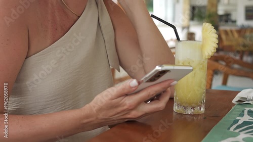 Woman using phone in cafe with tropical drink phone digital lifestyle and remote work concept Phone communication for blogger freelancer social media manager and entrepreneur enjoying modern leisure
