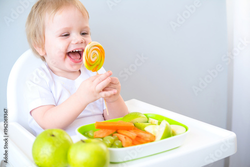 cute baby eating lollipop sitting in a baby chair. weaning