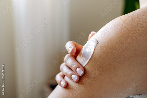 Close up female hands and a smear of cream or lotion or serum on the skin, woman applies moisturizing cream or lotion after showering, daily body skin care routine