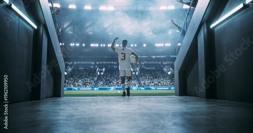 White Male Soccer Player Carries the Match Game Ball From the Tunnel Onto the Pitch, Saluting Supporters Before an International Championship Game in a Packed Stadium, World LEague Cup Event.