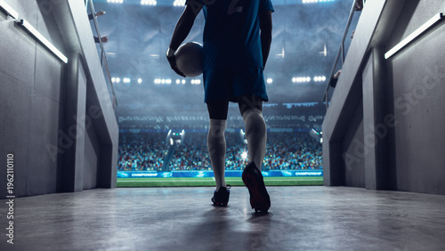 Fotografía Black Male Soccer Player Walks From the Stadium Tunnel Onto the Pitch Holding the Ball Before a Professional International Football Match, With a Full Arena Set for a Major World Euro Tournament