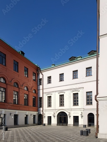 Low angle view of modern apartment buildings meeting under clear blue sky.