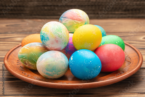 Beautiful tie-dye Easter eggs on a plate on a wooden table