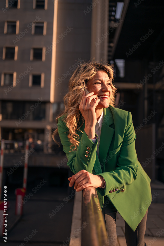 Fototapeta premium Businesswoman smiling during phone call at golden hour