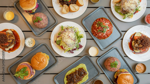 Variety of burgers and salads on plates and trays on wooden table