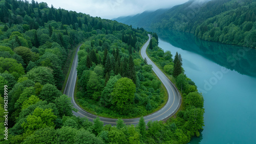 winding road through lush green forest by calm lake water  serene landscape view