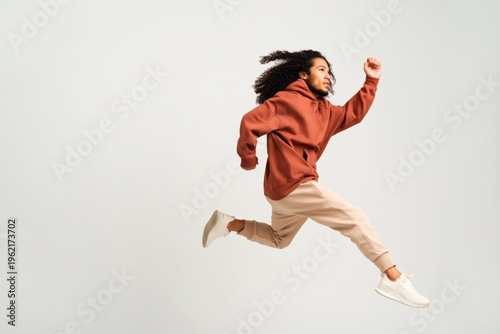 Young man leaping midair in studio against plain background