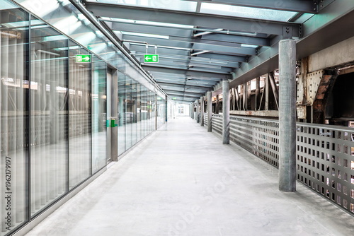 Tableau sur toile Modern industrial walkway with glass walls, steel beams and concrete floor in a bright office or public building