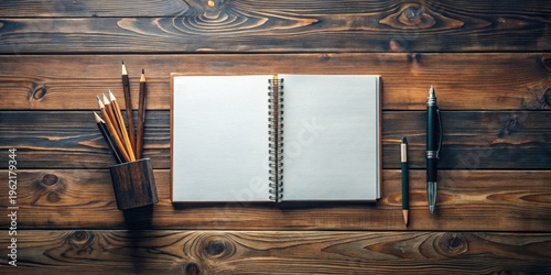 Open spiral notebook with pencils and pens on wooden surface