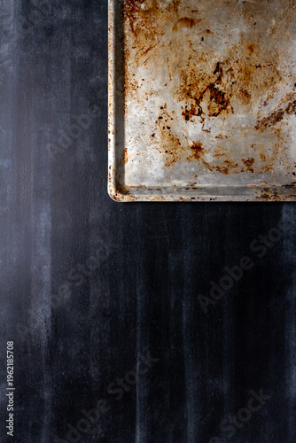 Used oven flat baking pan with burned spots and scratches on black chalkboard background