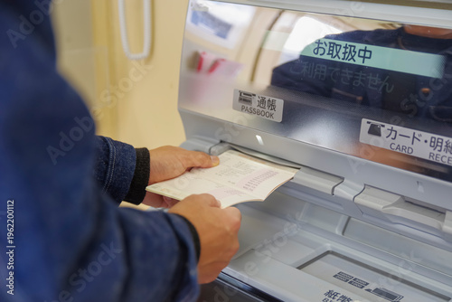 Photos 銀行ATMで通帳記帳を行う利用者