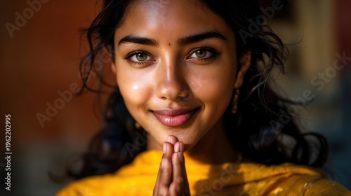 Jeune femme souriante aux mains jointes portant un vêtement jaune