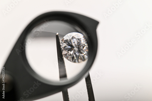 Diamond viewed through a magnifying glass held by tweezers