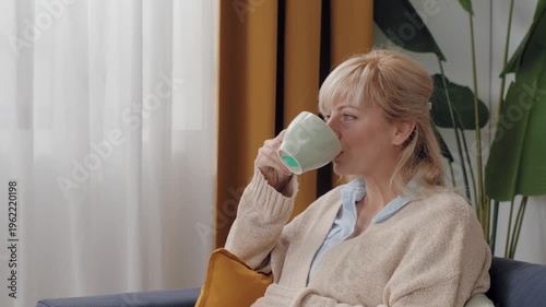 Mature blonde woman drinking tea looking thoughtful
