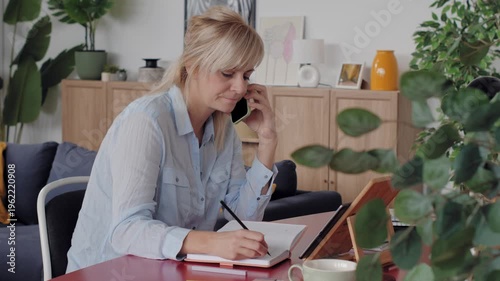 Businesswoman talking on phone and writing in notebook
