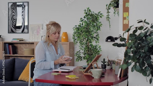 Mature woman working from home office answering a phone call