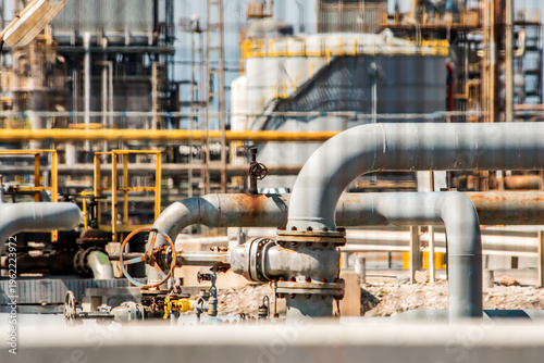 Photos Industrial pipes, valve system inside refinery with metal structures, processing equipment in background