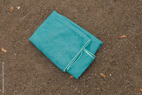 A bright blue piece of fabric is laying flat on a rough ground. The scene shows no people nearby
