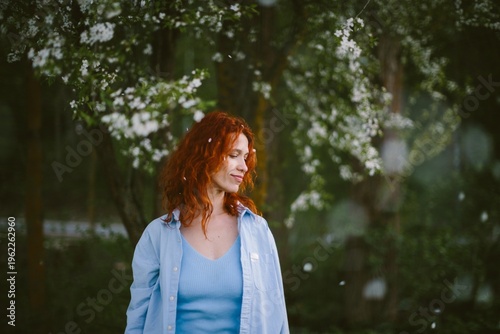 Schilderij op canvas Red haired woman enjoying falling spring blossoms