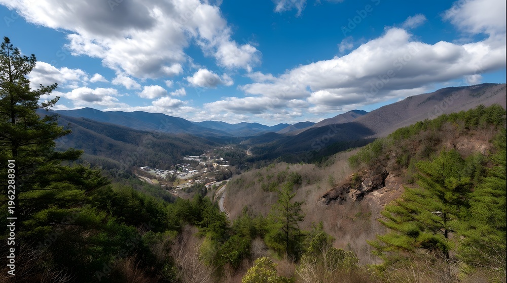 Fototapeta premium Expansive scenic panorama of a mountain valley town under a bright blue sky with scattered clouds