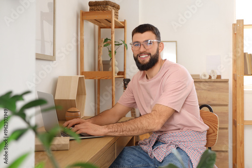 Young bearded man using laptop on table at home