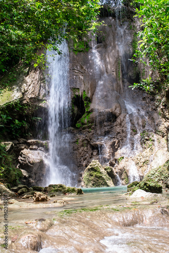 Beautiful Alam Kandung Waterfall in Tulungagung, East Java, Indonesia. Cascading water flows over rocky cliffs into a clear turquoise pool, surrounded by lush jungle.