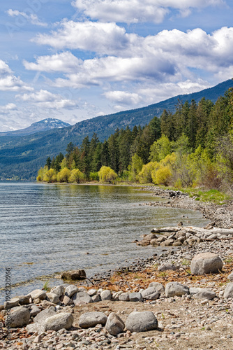 Mountains rise above the beach of Okanagan Lake at the Evely Recreation Site, British Columbia, Canada