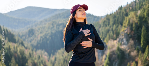 Relaxed woman breathing fresh air in a green pine forest and making breathing exercises 