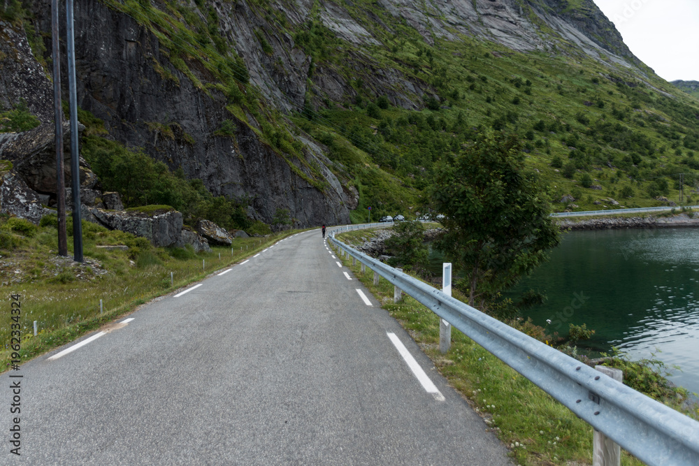 Obraz premium Narrow Mountain Road Beside Lake and Steep Rocky Cliffs