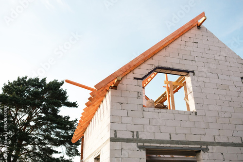 Konstfotografi Modern white block house at step of affixing roof rafters, timber lag layout visible, credit used for home-building, financial security by insurance